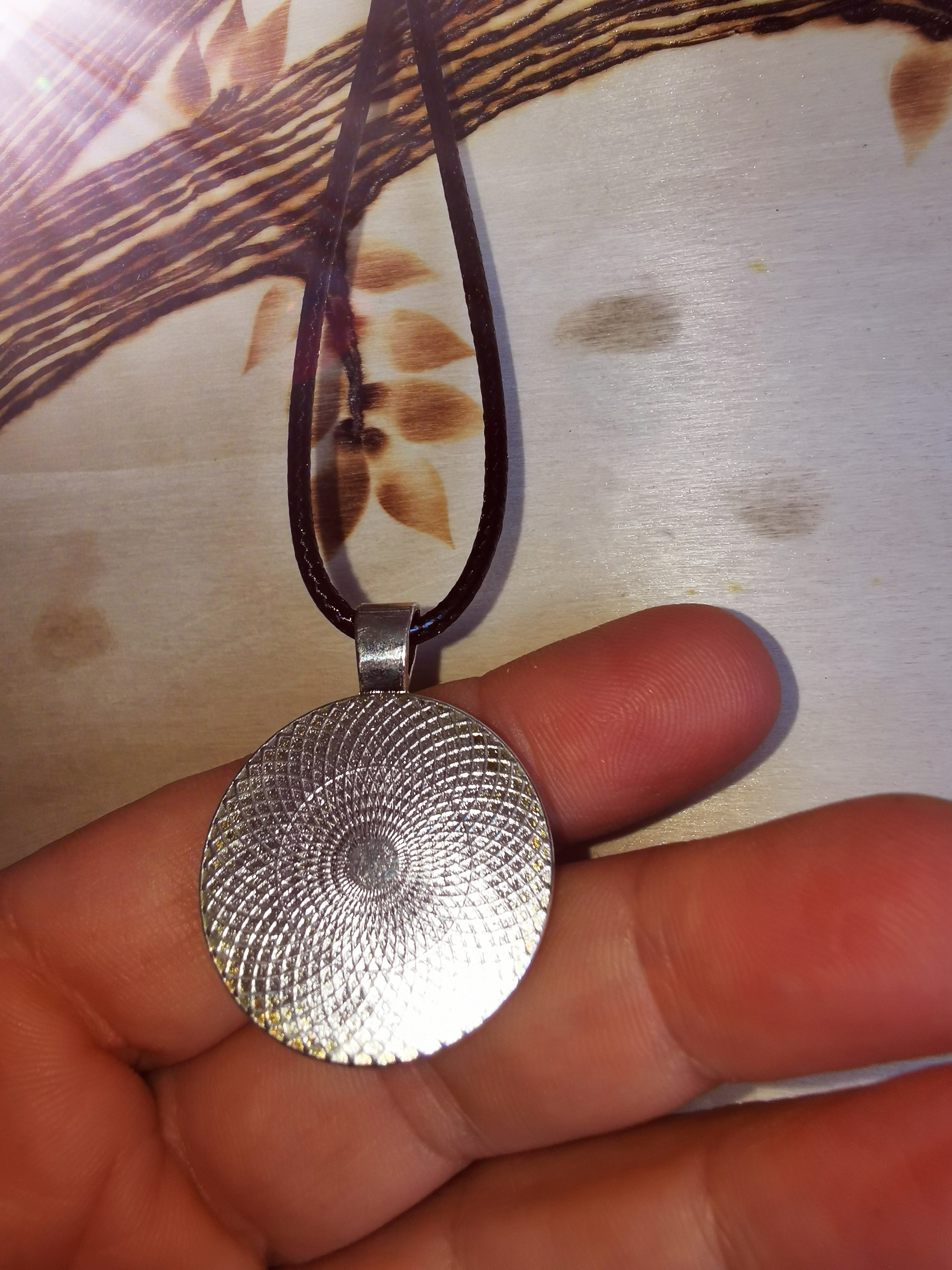 Pendentif fleuri en résine, bijou unique avec une fleur séchée dans un design argenté.